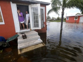 Quintana and Liz Perez look out at the flooding outside their home in the aftermath of Hurricane Irma in Immokalee, Fla., Monday, Sept. 11, 2017. (AP Photo/Gerald Herbert)