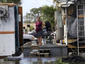 In this Sept. 11, 2017 file photo, Elida Dimas looks at floodwaters from her porch, in the aftermath of Hurricane Irma, in Immokalee, Fla. Irma badly damaged Dimas' mobile home and destroyed another she and her husband used for rental income, making their tough life even harder. (AP Photo/Gerald Herbert)