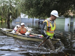 Cory Donoher pulls Linda DeWalt and her dogs on his kayak down a street in Jacksonville, Fla., Monday, Sept. 11, 2017, after it was flooded from the Ortega River when Hurricane Irma passed over the region. (Dede Smith/The Florida Times-Union via AP)