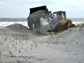 A Jacksonville Beach public works front loader moves sand to fortify the dunes near the Jacksonville Beach Fishing Pier, Friday, Sept. 8, 2018, in Jacksonville Beach, Fla., to help with a possible storm surge from Hurricane Irma. (Bob Mack/The Florida Times-Union via AP)