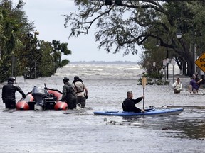Rescue workers, left, search a neighborhood for flood victims as a man on a kayak down the street after Hurricane Irma brought floodwaters to Jacksonville, Fla. Monday, Sept. 11, 2017. (AP Photo/John Raoux)