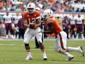 Miami quarterback Malik Rosier (12) hands off the football to running back Mark Walton during the first half of an NCAA college football game against Bethune-Cookman , Saturday, Sept. 2, 2017, in Miami Gardens, Fla. (AP Photo/Lynne Sladky)