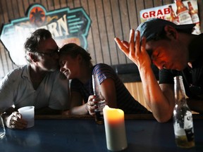 Carl Kesser and his children, Kia Kesser and Jason Kesser (L-R) hunker down by candlelight at the Tavern In the Grove bar after hurricane Irma on September 11, 2017 in Miami, Florida. )