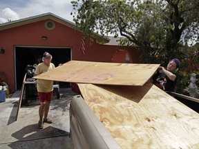 Stan Kreuter, 71, left, and his wife Jackie Kreuter, 56, Gulfport, Fla.,, load plywood in front of their home to take to their downtown Gulfport store Tuesday, Sept. 5, 2017, so they can board it up. Jackie Kreuter, along with her mother, husband, sister, daughter, grandson, five dogs and a bird are boarding up their home and business and leaving for Ocala to get out of Hurricane Irma's way