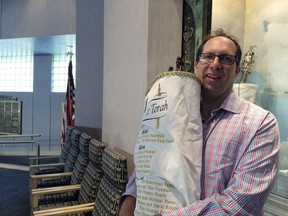 In this Sept. 18, 2017 photo, Rabbi Adam Miller of Temple Shalom in Naples, Fla., holds the Torah he took to Tennessee to protect it from Hurricane Irma. Miller has rewritten his Rosh Hashanah sermon to reflect the damage done to southwest Florida by the storm. During Hurricane Irma, Temple Shalom served as a sanctuary of a different kind. When the storm changed course at the last minute, the synagogue became an emergency shelter. As power stayed off for days, the temple served as a cooling center where neighbors could have a free meal. (AP Photo/Terry Spencer)