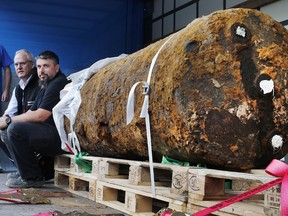 Dieter Schwaetzler, left, and Rene Bennert sit next to a 1.8 ton bomb right after they defused it, in Frankfurt, Germany, Sunday, Sept. 3, 2017.