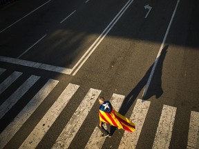 A man with an esteleda, or Catalonia independence flag, walks along a pedestrian crossing before the 'Yes' vote closing campaign in Barcelona, Spain, Friday, Sept. 29, 2017. Catalonia's planned referendum on secession is due be held Sunday by the pro-independence Catalan government but Spain's government calls the vote illegal, since it violates the constitution, and the country's Constitutional Court has ordered it suspended. (AP Photo/Francisco Seco)