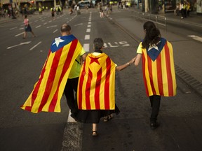 Family members wearing estelada or independence flags on their back walk at the end of a big rally during the Catalan National Day in Barcelona, Spain, Monday Sept. 11, 2017.  Some thousands rally in Barcelona to show support for an independent Catalan nation and the right to vote in a controversial referendum that has been banned by Spain. (AP Photo/Francisco Seco)