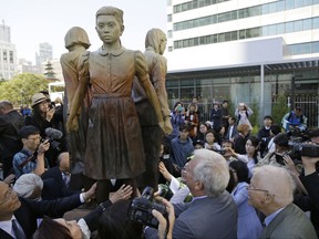 People move in to take a closer look at the "Comfort Women" monument after it was unveiled Friday, Sept. 22, 2017, in San Francisco. The monument was dedicated to the young women victims of Japanese military sexual slavery from 1932 until the end of World War II in 1945. (AP Photo/Eric Risberg)