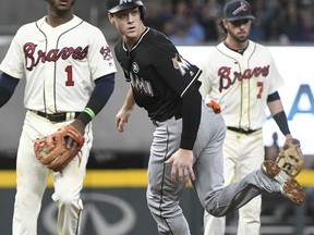 Miami Marlins' Brian Anderson rounds second base past Atlanta Braves second baseman Ozzie Albies (1) and shortstop Dansby Swanson (7) as he looks back at a ball hit by A.J. Ellis that goes to right field after an error by first baseman Freddie Freeman during the fourth inning of a baseball game, Saturday, Sept. 9, 2017, in Atlanta. (AP Photo/John Amis)