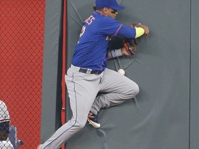 New York Mets center fielder Juan Lagares crashes into the wall as he tries to catch a ball hit for a double by Atlanta Braves' Ozzie Albies during the first inning of a baseball game Friday, Sept. 15, 2017, in Atlanta. (AP Photo/John Bazemore)