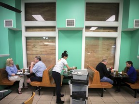 Henry's Restaurant manager Nhi Brayman, center, cleans a table while customers eat breakfast behind boarded up windows, Sunday, Sept., 10, 2017, in downtown Savannah, Ga. Hurricane Irma is expected effect parts of Georgia as early as Sunday night. (AP Photo/Stephen B. Morton)