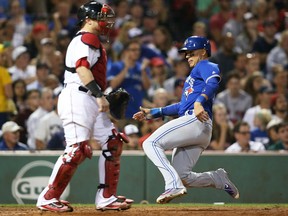 Ryan Goins of the Toronto Blue Jays scores in the sixth inning while Boston Red Sox catcher Christian Vazquez can only watch during MLB action Monday night at Fenway Park. The Jays were 10-4 winners.
