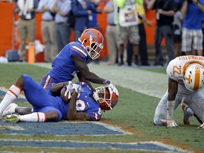 Florida wide receiver Tyrie Cleveland, bottom left, celebrates his game winning touchdown with teammate wide receiver Brandon Powell as Tennessee defensive back Micah Abernathy (22) hangs his head dejected as time expired in an NCAA college football game, Saturday, Sept. 16, 2017, in Gainesville, Fla. Florida won 26-20. (AP Photo/John Raoux)