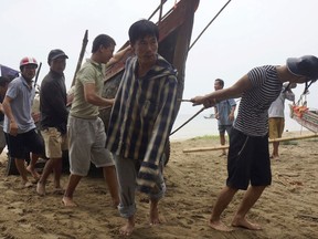 Vietnamese villagers move a fishing boat on shore in northern Thanh Hoa province, Vietnam, Thursday, Sept. 14, 2017. Vietnam on Thursday was bracing for typhoon Doksuri, which is expected to be the most powerful tropical cyclone to hit the Southeast Asian country in several years. (Trinh Duy Hung/Vietnam News Agency via AP)