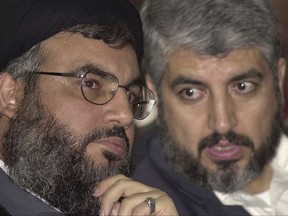 FILE -- In this March 27, 2004 file photo, Sheik Hassan Nasrallah, leader of Hezbollah guerrilla group, left, chats with Khaled Mashaal, head of Hamas' political bureau during a Hezbollah rally held in south of Beirut, Lebanon, to mark the assassination of Hamas founder Sheik Ahmed Yassin. Iran is working to restore a lost link in its network of alliances in the Middle East, trying to bring Hamas fully back into the fold after the Palestinian militant group had a bitter fall-out with Syria over that country's civil war. Iran and Hezbollah are quietly trying to mediate reconciliation between Syria and Hamas. If they succeed, it would shore up the alliance at a time when Iran is building a bloc of support across the region to counter Israel and the United States' Arab allies. (AP Photo/Hassan Ammar, File)