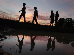 Villagers are silhouetted as they walk through a rice paddy during sunset on the outskirts of Phnom Penh, Cambodia, Tuesday, Sept. 12, 2017. (AP Photo/Heng Sinith)