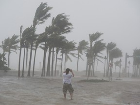 A man stands in a flooded street on the waterfront of Fort Lauderdale, Fla., to take photos as Hurricane Irma passes through on Sunday, September 10, 2017.