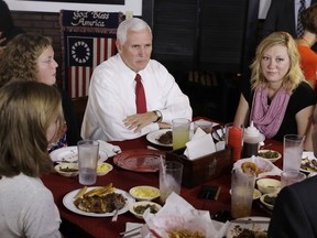 Vice President Mike Pence talks with the McCurry family during a visit to The Pittt Barbecue & Grill, Friday, Sept. 22, 2017, in Anderson, Ind. (AP Photo/Darron Cummings)
