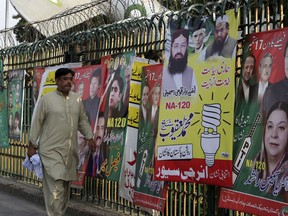 A man walks past posters of candidates contesting the election in Lahore, Pakistan, Thursday, Sept. 14, 2017. A Pakistani man with links to a U.S.-designated terrorist group is among four politicians running for a parliamentary seat vacated by former Prime Minister Nawaz Sharif. (AP Photo/K.M. Chaudary)