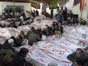 FILE - In this Tuesday, Feb. 19, 2013 file photo, Pakistani Shiite Muslims mourn next to the bodies of their relatives, a victims of bombing that killed scores of people in Quetta, Pakistan. Thousands of Pakistani and Afghan Shiites have been recruited by Iran to fight in Syria generating fears that their return could aggravate sectarian rivalries, say counterterrorism officials as well as analysts, who track militant movements.(AP Photo/Arshad Butt, File)