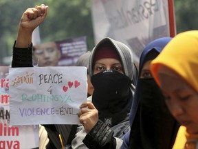 A Muslim woman raises her fist as she holds a poster during a rally against persecution of Myanmar's Rohingya Muslim minority, outside Myanmar Embassy in Jakarta, Indonesia, Monday, Sept. 4, 2017. Hundreds of Muslim women staged the rally on the third day of protests calling for the government of the world's most populous Muslim country to take a tougher stance against persecution of the Rohingya. (AP Photo/Tatan Syuflana)