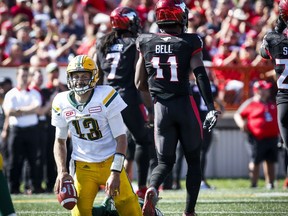 Edmonton Eskimos' quarterback Mike Reilly, left, picks himself up after being sacked by Calgary Stampeders' Junior Turner, centre, and teammate Josh Bell during second half CFL football action in Calgary, Monday, Sept. 4, 2017. THE CANADIAN PRESS/Jeff McIntosh
