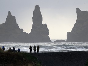 People walk on the black sanded beach in Vik, Iceland, near the Volcano Katla, Wednesday, Oct. 26, 2016.