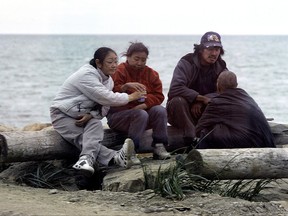 In this Aug. 11, 2007 file photo a group of people pass around a can of beer as they sit on a seawall in Nome, Alaska. The old Gold Rush town of Nome on Alaska's western coast is again trying to address the hard drinking that's deeply entrenched there, this time with a proposed law prohibiting intoxication in public places like the main street, where drunks can be seen stumbling along or passed out near tourist shops. (AP Photo/Al Grillo,File)