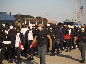 FILE - In this June 23, 2017 file photo Italian border police officers escort sub Saharan men on their way to a relocation center, after arriving in the Golfo Azzurro rescue vessel at the port of Augusta, in Sicily, Italy, with hundreds of migrants aboard, rescued by members of Proactive Open Arms NGO. The European Court of Justice says it has rejected efforts by Hungary and Slovakia to stay out of a European Union scheme meant to relocate refugees. The court said Wednesday, Sept. 6, 2017 that it had "dismissed in its entirety the actions brought by Slovakia and Hungary." (AP Photo/Emilio Morenatti, file)