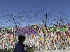 A visitor walks by the wire fence decorated with ribbons carrying messages to wish for the reunification of the two Koreas at the Imjingak Pavilion in Paju, South Korea, Wednesday, Sept. 13, 2017. South Korea said Wednesday it conducted its first live-fire drill for an advanced air-launched cruise missile it says will strengthen its pre-emptive strike capability against North Korea in the event of crisis. (AP Photo/Lee Jin-man)