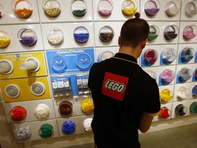 FILE- In this Tuesday, April 5, 2016 file photo, an employee sorts Legos in the the new LEGO flagship store unveiled as part of the new Les Halles shopping mall during the press visit in Paris. Danish toy maker Lego said Tuesday, Sept. 5, 2017, it will cut 1,400 jobs, or about eight percent of its global workforce, after reporting a decline in sales and profits in the first half of 2017. (AP Photo/Francois Mori, File)