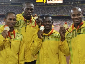 FILE - In this Saturday, Aug. 23, 2008 file photo, Jamaica's men's 4x100 meters relay team, from left, Michael Fraser, Usain Bolt, Nesta Carter and Asafa Powell show their gold medals during the athletics competitions in the National Stadium at the Beijing 2008 Olympics in Beijing. An appeal case involving the 2008 Olympic title stripped from Usain Bolt's Jamaica relay team is going to court in November 2017. (AP Photo/Petr David Josek, File)
