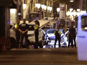 FILE - In this Thursday, Aug. 17, 2017 file photo police officers stand next to the van involved on an attack in Las Ramblas in Barcelona, Spain. The investigation into last month's attacks in Spain is becoming increasingly international. Among the focus of authorities are plane tickets to Brussels, a lightning trip to Paris and an itinerant imam who went from trafficking people and drugs to secretly preaching jihad to young Muslims in northeastern Spain. (AP Photo/Manu Fernandez, File)