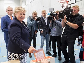 Norway's Prime Minister Erna Solberg casts her ballot at a polling station in Bergen, Norway, during the general election on Monday Sept. 11, 2017. In the background at left is her husband, Sindre Finnes. Norway's national election is a tight contest over national values, including how welcoming the wealthy country should be to migrants and asylum-seekers and how close it should be to the European Union. (Marit Hommedal/NTB Scanpix via AP)