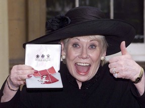 FILE - This is a Oct. 24, 2000  file photo of British  actress Liz Dawn at Buckingham Palace, London after she received an MBE.  Liz Dawn, the actress who played tart-tongued Vera Duckworth in the long-running British soap opera "Coronation Street,"  died on Monday Sept. 25, 2017 . She was 77. (Sean Dempsey/PA via AP)