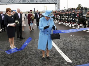 Britain's Queen Elizabeth II, cuts the ribbon to officially open the Queensferry Crossing in Scotland, watched by Scotland's First Minister Nicola Sturgeon, left,,  during the official opening of the new bridge across the Firth of Forth, Monday Sept.  4, 2017. Kensington Palace said Monday that Prince William and his wife, Kate Duchess of Cambridge, are expecting their third child. The announcement released in a statement Monday says the queen is delighted by the news. William and his wife, Kate, already have two children, Prince George and Princess Charlotte.(Andrew Milligan/PA via AP)