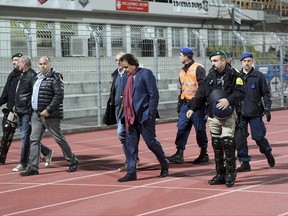 In this photo taken Thursday, Sept. 21, 2017 Sion's President Christian Constantin, center, is escorted by police during the Super League soccer match FC Lugano against FC Sion, at the Cornaredo stadium in Lugano, Switzerland. The senior official with Sion's bid to host the 2026 Winter Olympics has stepped down while being investigated by the Swiss soccer league over a physical confrontation with a television analyst. (Samuel Golay/Ti-Press/Keystone via AP)