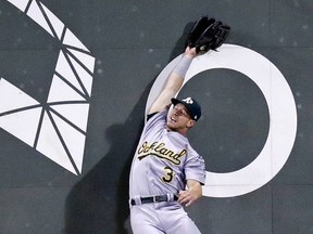 Oakland Athletics center fielder Boog Powell leaps high for an off-the-wall double by Boston Red Sox's Andrew Benintendi during the third inning of a baseball game at Fenway Park in Boston, Wednesday, Sept. 13, 2017. (AP Photo/Charles Krupa)