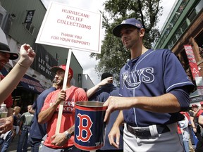 Florida Panthers' Vincent Trocheck, center left, holds a sign as he Tampa Bay Rays' Steve Cishek, right, collect donations outside Fenway Park in Boston for relief efforts that may be needed because of Hurricane Irma, before a baseball game between the Rays and the Boston Red Sox, Sunday, Sept. 10, 2017, in Boston. (AP Photo/Steven Senne)