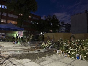 An improvised memorial of flowers and candles sprouted on the corner of Torreon and Viaducto continues to grow in size, in Mexico City's Navarate neighborhood, Friday, Sept. 29, 2017. Eleven people reportedly died when the six-story, mixed-use building collapsed during Mexico's Sept. 19 earthquake. (AP Photo/Moises Castillo)