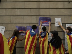 Students fix banners on the wall regarding the referendum in Barcelona, Spain, Thursday, Sept. 28, 2017. Thousands of striking university students are marching through Barcelona to protest an intensifying central government crackdown on Sunday's planned independence referendum in Catalonia. Banners reads in Catalan: "Democracy". (AP Photo/Manu Fernandez)
