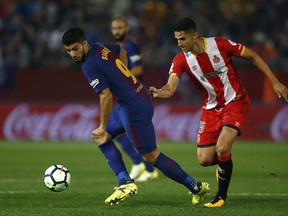 FC Barcelona's Luis Suarez, left, duels for the ball against Girona's Pedro Alcala during the Spanish La Liga soccer match between Girona and FC Barcelona at the Montilivi stadium in Girona, Spain, Saturday, Sept. 23, 2017. (AP Photo/Manu Fernandez)