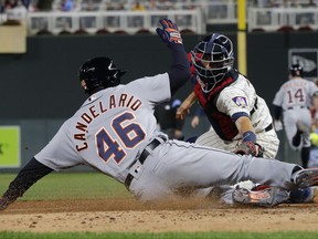 Detroit Tigers' Jaime Candelario, left, slides past Minnesota Twins' catcher Jason Castro to score after Castro dropped the ball during the fifth inning of a baseball game Saturday, Sept. 30, 2017, in Minneapolis. (AP Photo/Jim Mone)