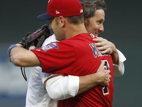 Former Minnesota Twins pitcher Joe Nathan, right, and  Twins' Joe Mauer hug after Mauer caught the ceremonial first pitch shortly after Nathan, the team's closer, signed a one-day contract to announce his retirement from baseball, prior to the Twins' game against the Kansas City Royals on Friday, Sept, 1, 2017, in Minneapolis. (AP Photo/Jim Mone)