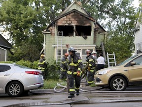 Firefighters look over the scene of a duplex fire that gutted the upstairs and left two seriously burned Thursday, Sept. 28, 2017, in Minneapolis.   Police say a woman was critically burned when a man set her on fire in a domestic dispute that also left him with severe burns.  (David Joles/Star Tribune via AP)