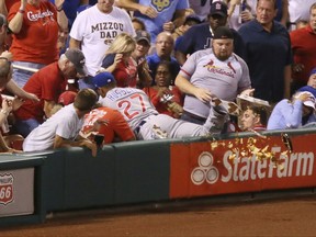 Chicago Cubs shortstop Addison Russell knocks over a fan's tray of nachos as he falls into the stands reaching for a foul ball hit by St. Louis Cardinals' Jedd Gyorko during the second inning of a baseball game Monday, Sept. 25, 2017, at Busch Stadium in St. Louis. Russell was unable to make the catch and Gyorko subsequently hit a solo home run. (Chris Lee/St. Louis Post-Dispatch via AP)