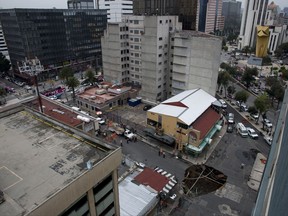 A sinkhole covers an intersection in downtown Mexico City, Thursday, Aug. 31, 2017. An enormous sinkhole about 30 feet (10 meters) in diameter opened on the street, caused by an accumulation of water, according to civil protection. (AP Photo/Eduardo Verdugo)