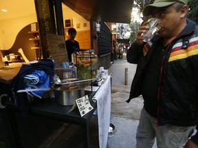 A man drinks a glass of water given to him by a restaurant in Mexico City's La Condesa neighborhood, Friday, Sept. 22, 2017, four days after the 7.1 earthquake. In the stylish Condesa neighborhood young revelers typically spill out from dimly lit bars and restaurants on a Friday night. But the first weekend since the 7.1-magnitude earthquake toppled buildings just blocks away began on a somber note. (AP Photo/Marco Ugarte)
