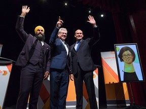 Jagmeet Singh, from left to right, Charlie Angus and Guy Caron pose for a photograph as Niki Ashton, is seen on a television screen via satellite from Ottawa, before the final federal NDP leadership debate in Vancouver on September 10, 2017.